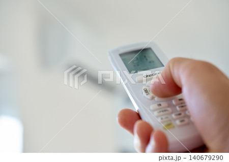 Hand pressing air conditioner remote control button 140679290