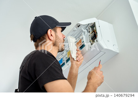 Man repairing wall mounted air conditioner Man repairing wall mounted air conditioner 140679294