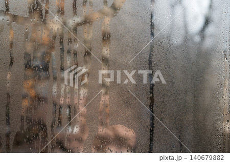 condensation covers a wet glass pane. Thick droplets slide slowly, leaving winding trails. wet glass. abstract background. condensation covers a wet glass pane. Thick droplets slide slowly, leaving winding trails. wet glass. abstract background. 140679882