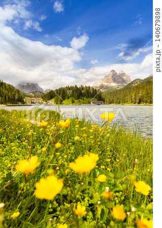 Colorful wildflowers on the shore of Lake Misurina with the iconic Tre Cime di Lavaredo rising above alpine forests in the background. Scenic summer landscape in the Dolomites, northern Italy. Colorful wildflowers on the shore of Lake Misurina with the iconic Tre Cime di Lavaredo rising above alpine forests in the background. Scenic summer landscape in the Dolomites, northern Italy. 140679898