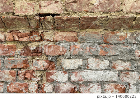 Close up of an old weathered brick wall with cracked plaster and exposed red bricks. Rustic grunge masonry texture background Close up of an old weathered brick wall with cracked plaster and exposed red bricks. Rustic grunge masonry texture background 140680225