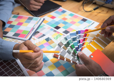Interior designer chooses a color chart for home design. Graphic designers working on color chart at modern office. Interior designer chooses a color chart for home design. Graphic designers working on color chart at modern office. 140680369