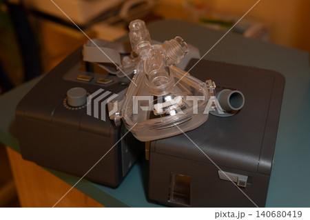 Medical cpap machine and breathing mask on a table for sleep apnea treatment in a home environment. Medical cpap machine and breathing mask on a table for sleep apnea treatment in a home environment. 140680419