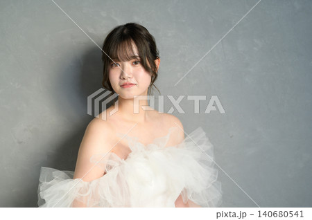 グレー背景で微笑む白いウェディングドレスの日本人女性 グレー背景で微笑む白いウェディングドレスの日本人女性 140680541