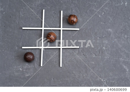 Chocolate balls placed in tic tac toe layout using white lines on dark surface. Chocolate balls placed in tic tac toe layout using white lines on dark surface. 140680699