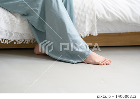 ベッドに座る女性の足元 140680812