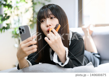 ベッドでスマホを見ながらドーナツを食べる日本人女性 ベッドでスマホを見ながらドーナツを食べる日本人女性 140680875
