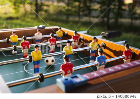 Foosball table with players and a ball on a green field, capturing casual recreation as a gateway to the Football World Cup Foosball table with players and a ball on a green field, capturing casual recreation as a gateway to the Football World Cup 140680948