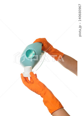 tilting a blue canister to pour gel into a white dispenser cap with gloved hands tilting a blue canister to pour gel into a white dispenser cap with gloved hands 140680967