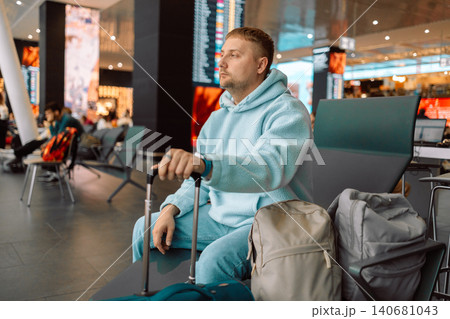Male traveler waiting at airport terminal with luggage 140681043