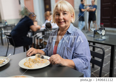 Happy senior woman enjoying lunch at outdoor cafe terrace during European vacation 140681112