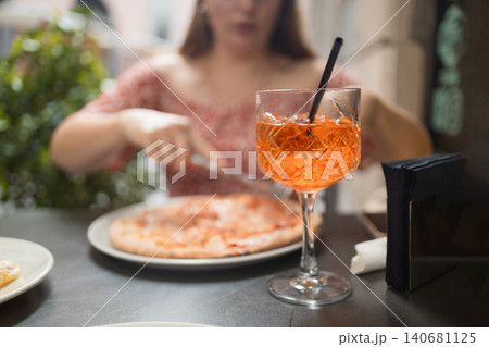 Close-up of Aperol Spritz cocktail and delicious pizza on outdoor restaurant table Close-up of Aperol Spritz cocktail and delicious pizza on outdoor restaurant table 140681125