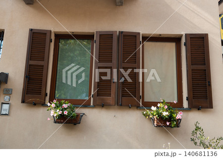 Traditional European windows with brown wooden shutters and beautiful flower boxes Traditional European windows with brown wooden shutters and beautiful flower boxes 140681136