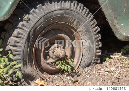 Old abandoned car showing rusty wheel and flat tire Old abandoned car showing rusty wheel and flat tire 140681368