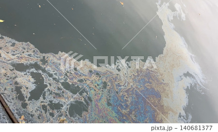 Iridescent oil slick polluting dark water surface 140681377