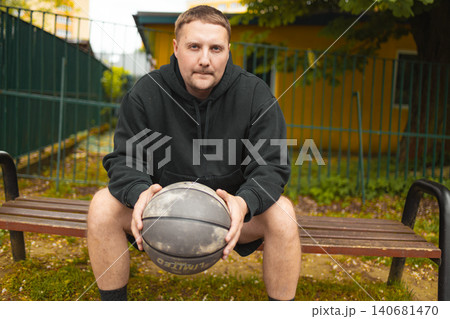 Portrait of basketball player sitting on bench with ball Portrait of basketball player sitting on bench with ball 140681470