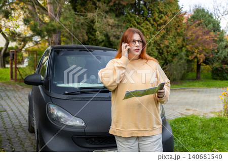 Woman talking on phone calling roadside assistance near car Woman talking on phone calling roadside assistance near car 140681540