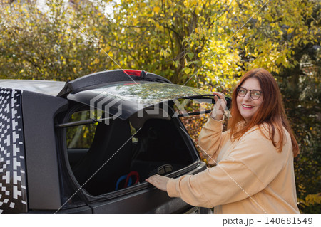 Woman packing luggage into car trunk for road trip Woman packing luggage into car trunk for road trip 140681549