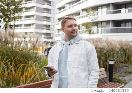 Man using smartphone near modern residential building Man using smartphone near modern residential building 140681550