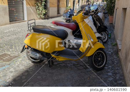 Bright yellow vintage motor scooter parked on old cobblestone street Bright yellow vintage motor scooter parked on old cobblestone street 140681590