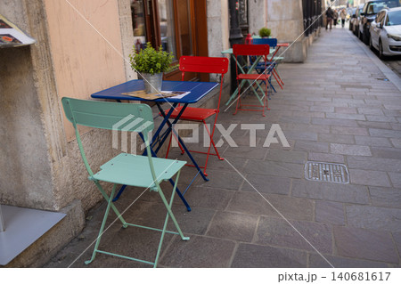 Empty colorful tables and chairs of an outdoor cafe on a narrow european street. 140681617