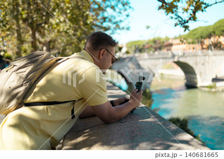 Young Caucasian man holding an action camera with gimbal stabilizer while vlogging outdoors. 140681665