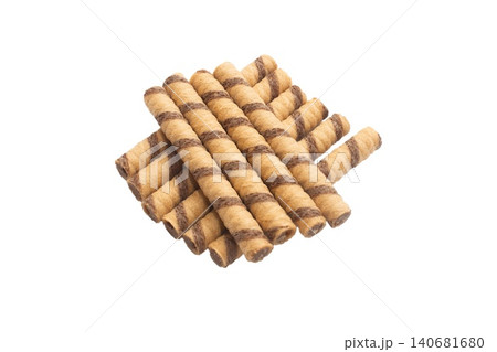 Close up photo of cylindrical wafer rolls filled with chocolate cream, arranged in a pyramid formation on a white background. Close up photo of cylindrical wafer rolls filled with chocolate cream, arranged in a pyramid formation on a white background. 140681680