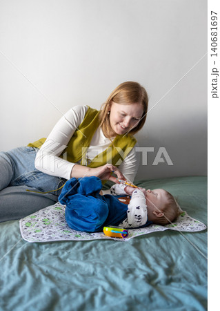 Young mother taking care of her baby boy on a bed at home. Young mother taking care of her baby boy on a bed at home. 140681697