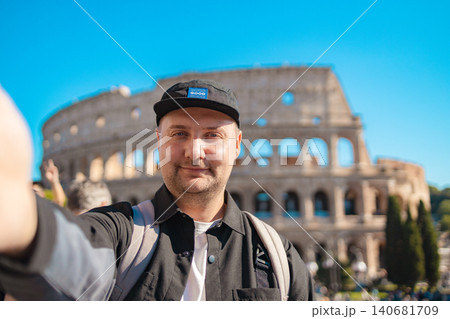 Handsome 30s tourist visiting Colosseum in Rome, Italy. Young man taking photo in front of famous Italian landmark Handsome 30s tourist visiting Colosseum in Rome, Italy. Young man taking photo in front of famous Italian landmark 140681709