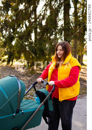 Woman walking with baby stroller in park Woman walking with baby stroller in park 140681799