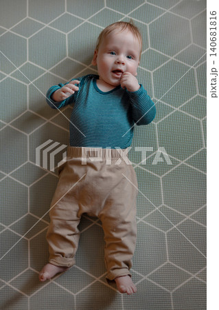 Adorable baby boy lying on a play mat and looking at camera Adorable baby boy lying on a play mat and looking at camera 140681816