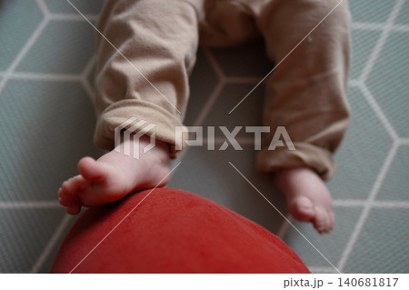 Close-up of cute baby feet resting on a red cushion at home Close-up of cute baby feet resting on a red cushion at home 140681817