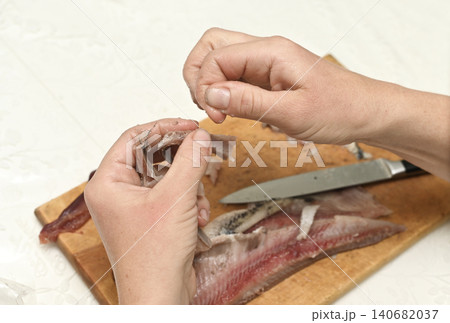 Hands cleaning herring fillet from skin and bones. 140682037