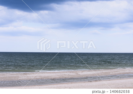 Wide ocean horizon meets cloudy sky above sandy beach shore. Wide ocean horizon meets cloudy sky above sandy beach shore. 140682038