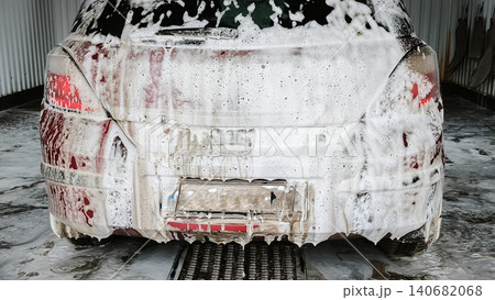 dirty car at car wash with soap foam covering the side and wheels. dirty car at car wash with soap foam covering the side and wheels. 140682068