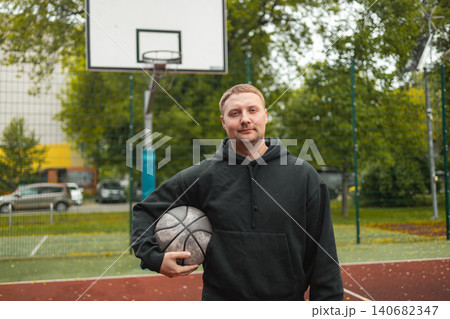 Portrait of smiling man holding basketball ball on court 140682347