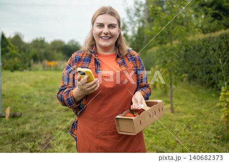 Happy young woman farmer holding strawberry box in garden 140682373