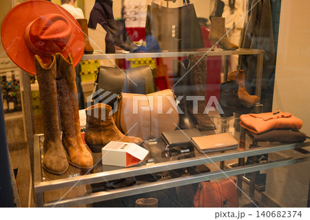 Luxury leather goods display with stylish cowboy boots and bags in European boutique window 140682374