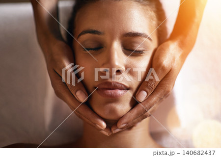Woman, spa and face massage on towel with hands and care for facial, wellness and beauty treatment on bed. Above, lens flare and african female person with skincare and relax at hotel with skin glow Woman, spa and face massage on towel with hands and care for facial, wellness and beauty treatment on bed. Above, lens flare and african female person with skincare and relax at hotel with skin glow 140682437