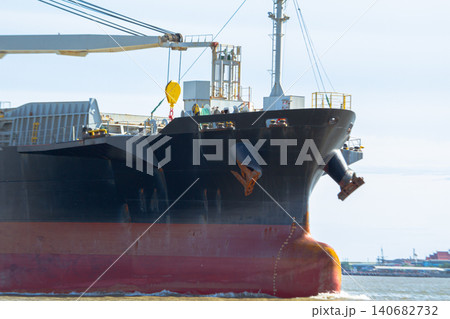 Cargo ship bow anchor ocean harbor steel crane sunlight, massive freighter near port with red hull and black paint, mooring gear and deck equipment under clear blue sky, maritime transport concept Cargo ship bow anchor ocean harbor steel crane sunlight, massive freighter near port with red hull and black paint, mooring gear and deck equipment under clear blue sky, maritime transport concept 140682732