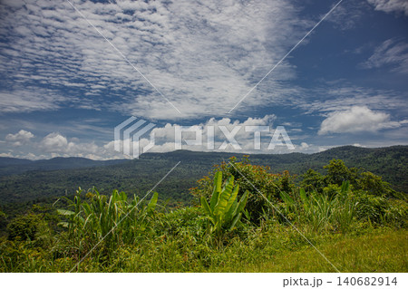 Tropical mountain rainforest valley cloud sky forest panorama, wide landscape view over lush green ridge and grass with banana plant under dramatic summer clouds, peaceful mood Tropical mountain rainforest valley cloud sky forest panorama, wide landscape view over lush green ridge and grass with banana plant under dramatic summer clouds, peaceful mood 140682914