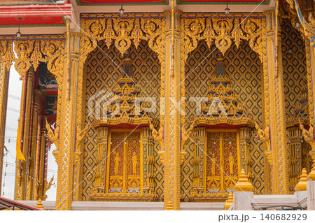 Thai temple golden facade ornate carving Buddhist architecture pattern window, detailed exterior with gilded relief, traditional motifs, bright sunlight, cultural heritage Thai temple golden facade ornate carving Buddhist architecture pattern window, detailed exterior with gilded relief, traditional motifs, bright sunlight, cultural heritage 140682929