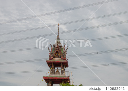 Temple pagoda spire ornate roof gable architecture wire against cloudy sky, traditional Asian shrine tower rising above street, calm atmosphere with intricate carved detail Temple pagoda spire ornate roof gable architecture wire against cloudy sky, traditional Asian shrine tower rising above street, calm atmosphere with intricate carved detail 140682941