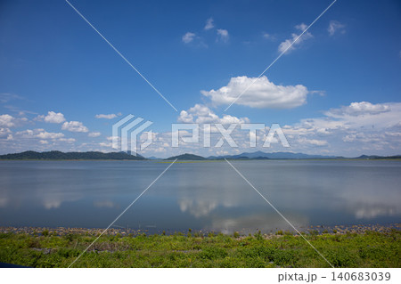 Lake calm water blue sky cloud mountain horizon reflection shoreline, wide tranquil landscape with distant ridge, summer daylight, open space for travel nature background 140683039