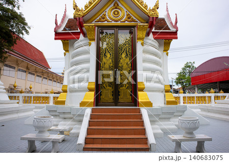 Ornate temple entrance with golden door, white shrine exterior, red roof, and stone steps in quiet asian courtyard 140683075