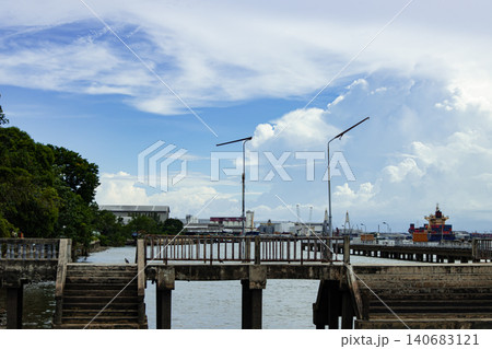 Harbor waterfront with bridge, pier, dock, cloudy sky, and calm water near industrial port landscape Harbor waterfront with bridge, pier, dock, cloudy sky, and calm water near industrial port landscape 140683121
