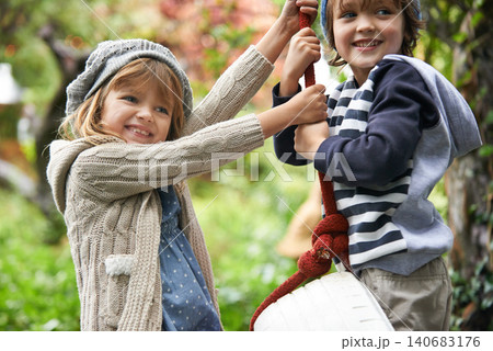 Children, smile and swing in a backyard in winter together with sibling and fun in garden. Youth, nature and excited on tire in fall at home outdoor with kids playing by tree with happy girl and boy 140683176