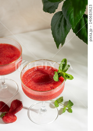 Strawberry daiquiri cocktail slushie with mint on white table Strawberry daiquiri cocktail slushie with mint on white table 140683623