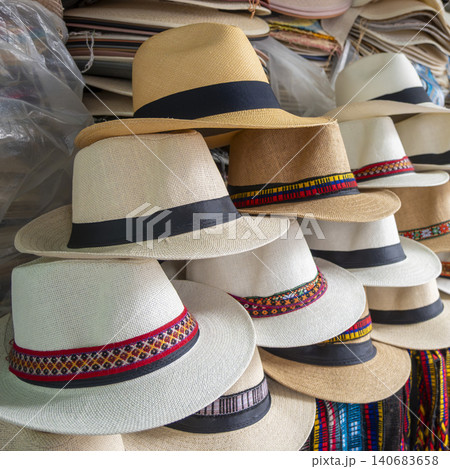 Close-up of handcrafted Ecuadorian toquilla straw hats stacked at a market stall. 140683658