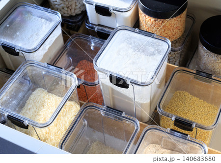 White flour and long rice in transparent pantry containers, organized kitchen drawer with airtight dry food boxes close up White flour and long rice in transparent pantry containers, organized kitchen drawer with airtight dry food boxes close up 140683680